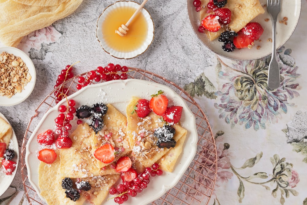 a plate of crepes topped with berries and powdered sugar