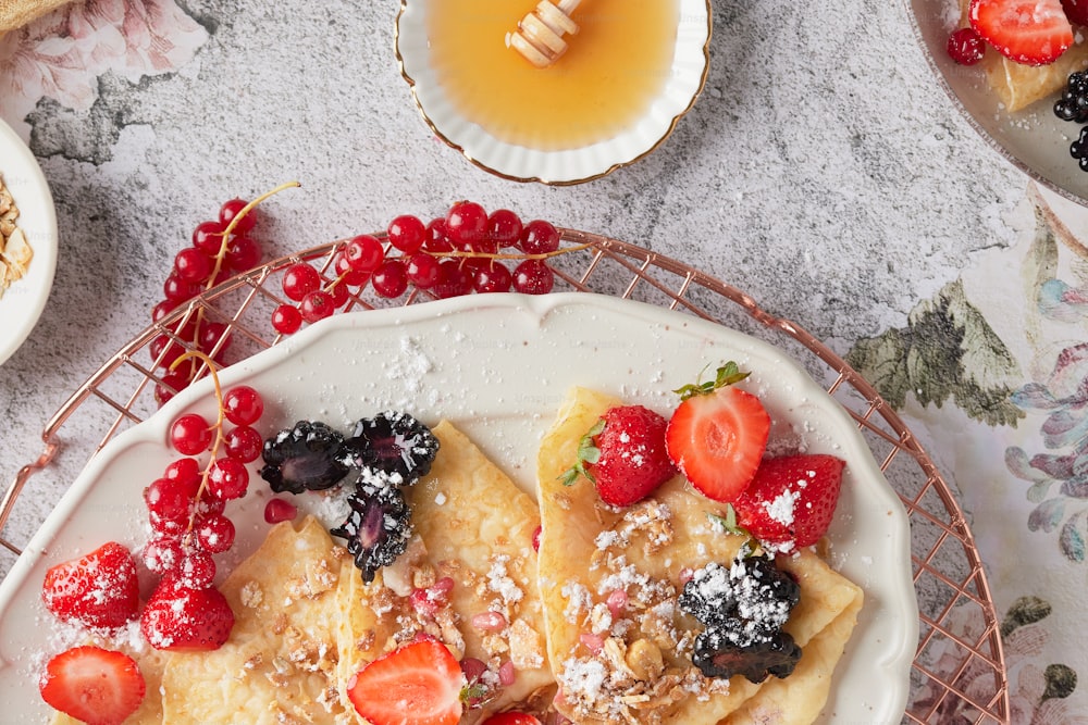 a plate of crepes topped with berries and powdered sugar