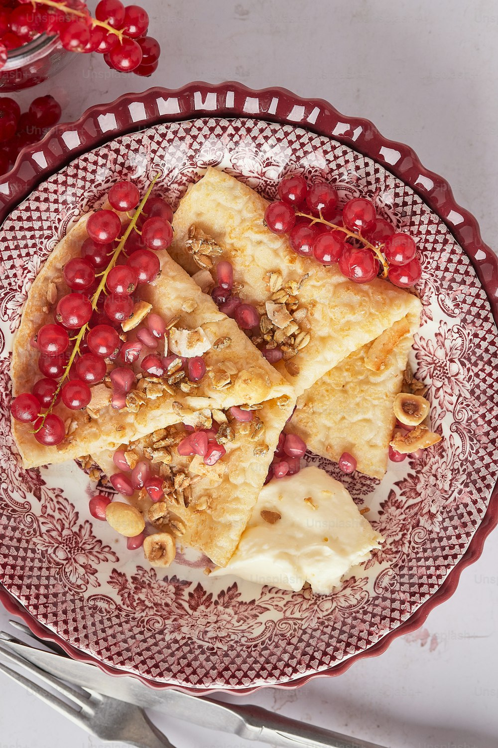 a red plate topped with crepes covered in fruit