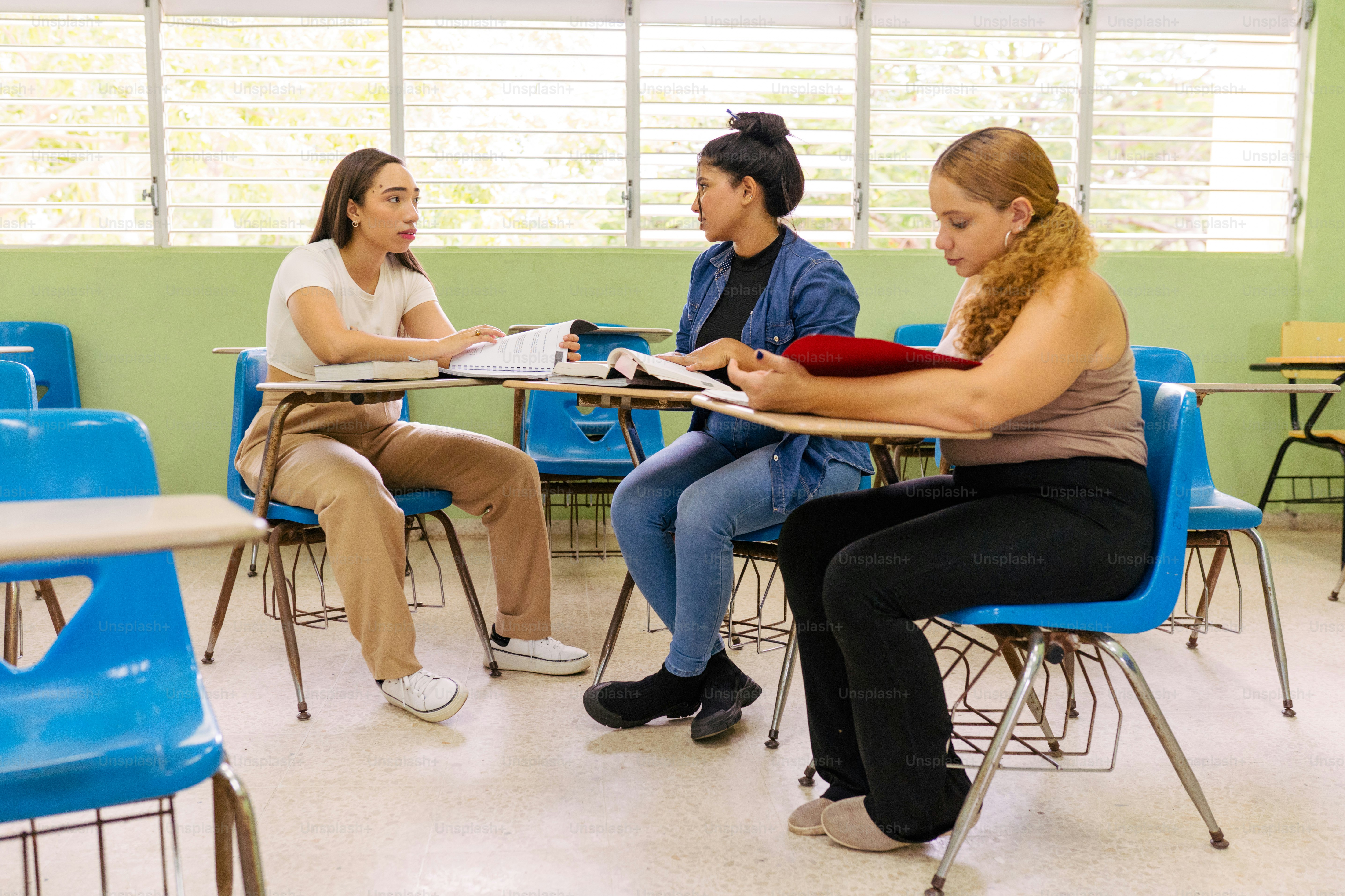 a group of women sitting at a table in a classroom