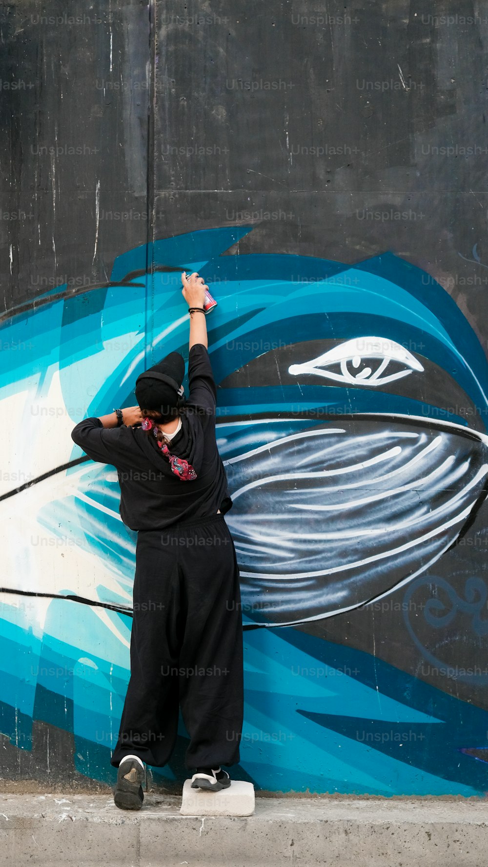 Un hombre está pintando un mural en el costado de un edificio