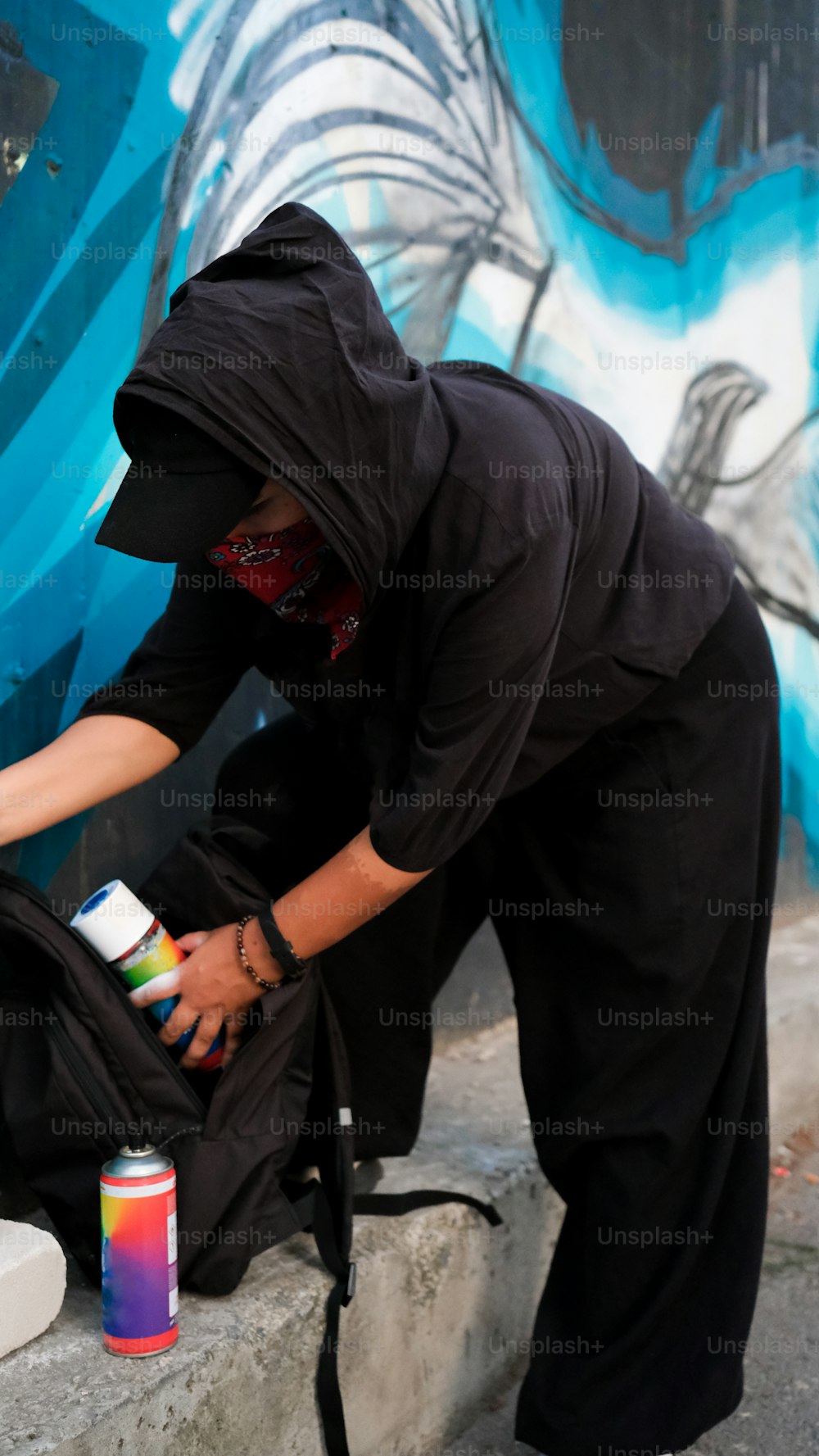 eine Person in einem schwarzen Outfit, die eine Wand streicht
