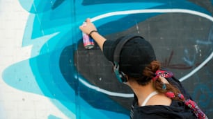 Una donna sta dipingendo un murale su un muro