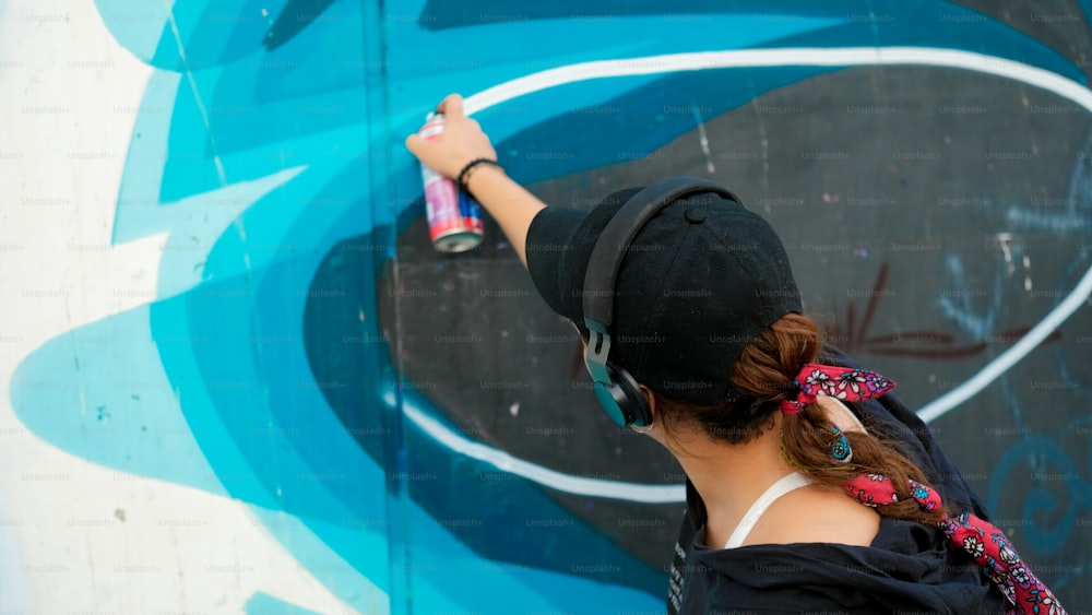 Eine Frau malt ein Wandbild an eine Wand