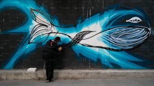 Un hombre pintando un pez en el costado de un edificio