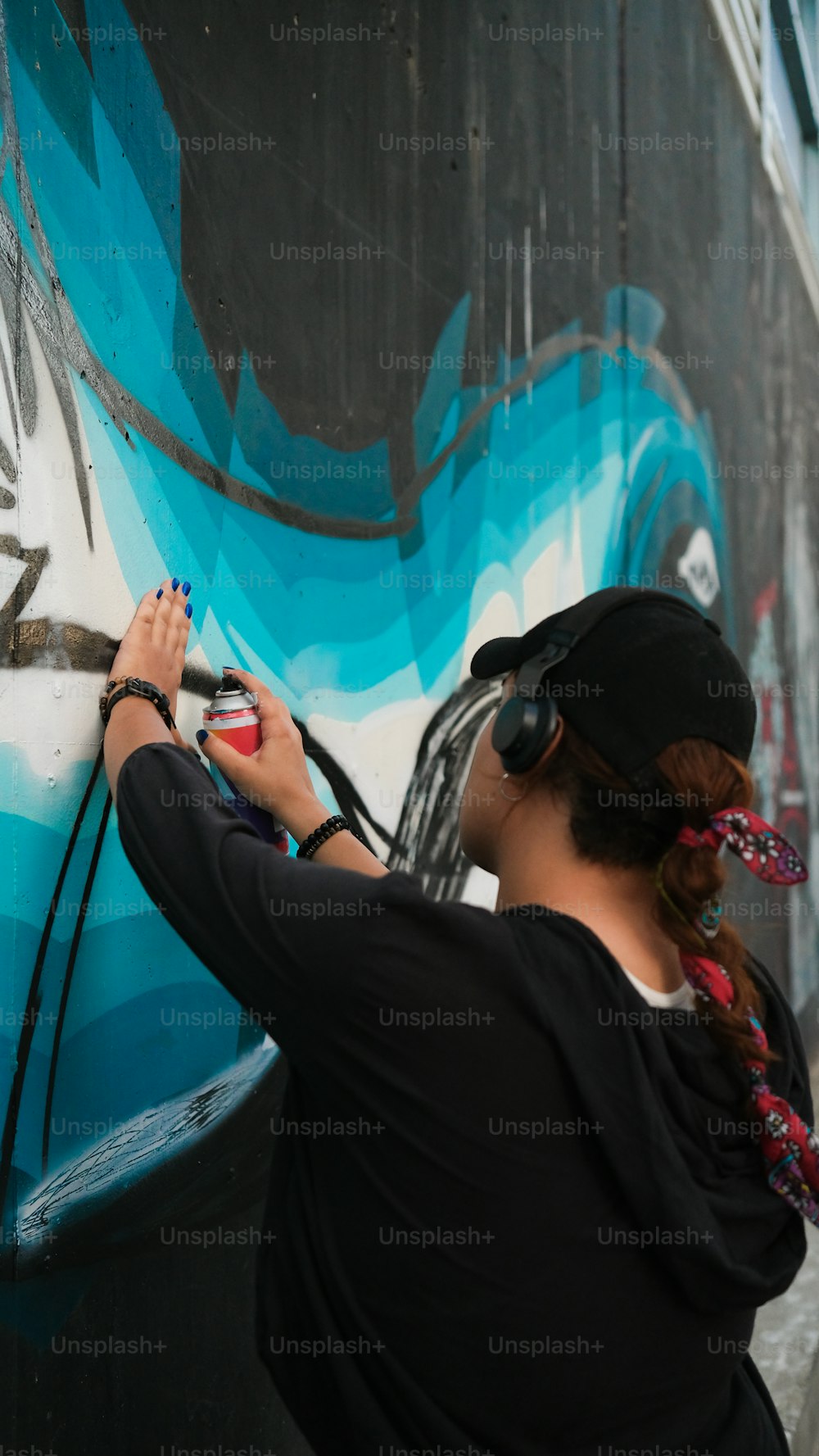 a woman is painting a wall with graffiti