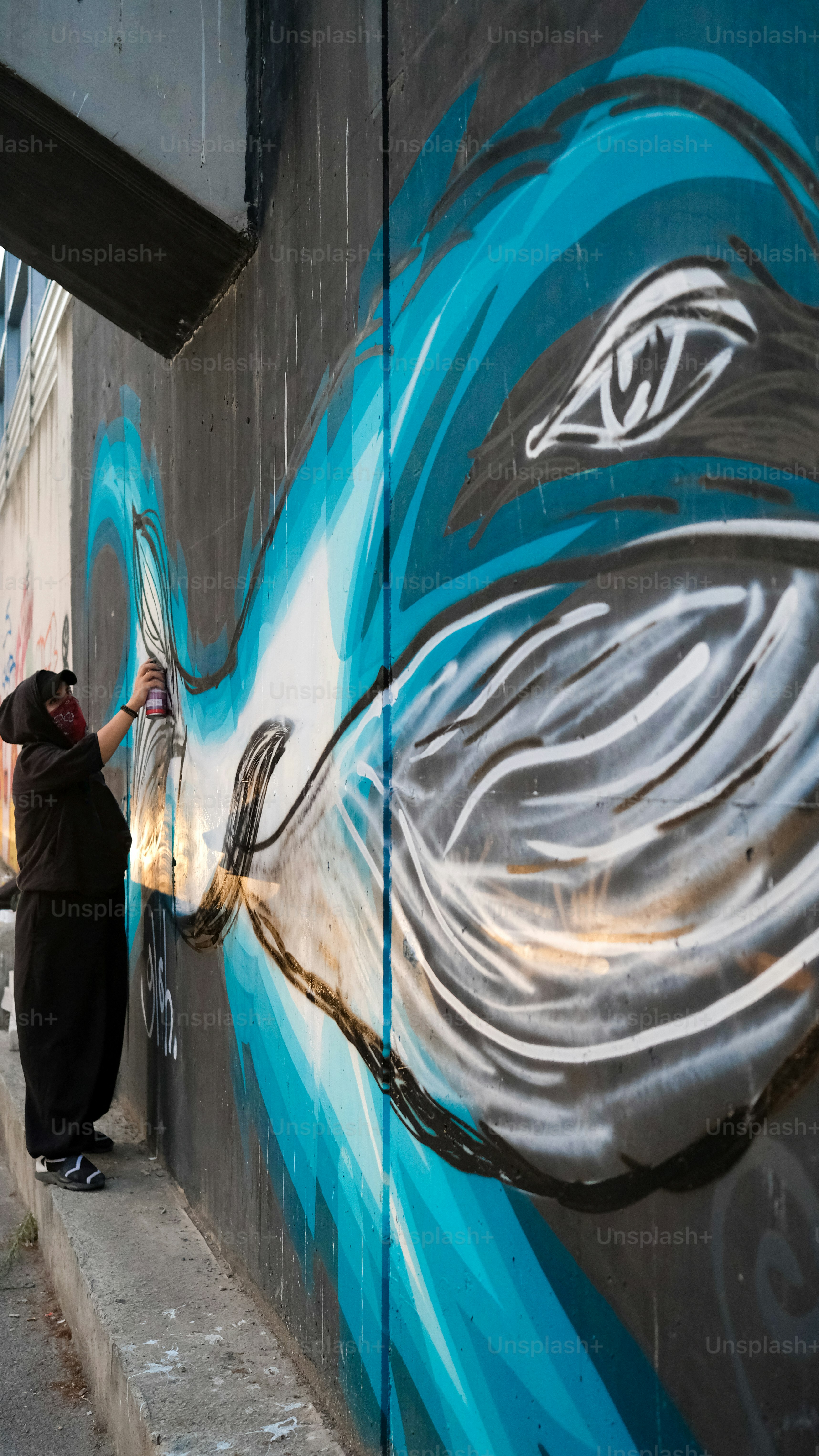 建物の側面に壁画を描く女性