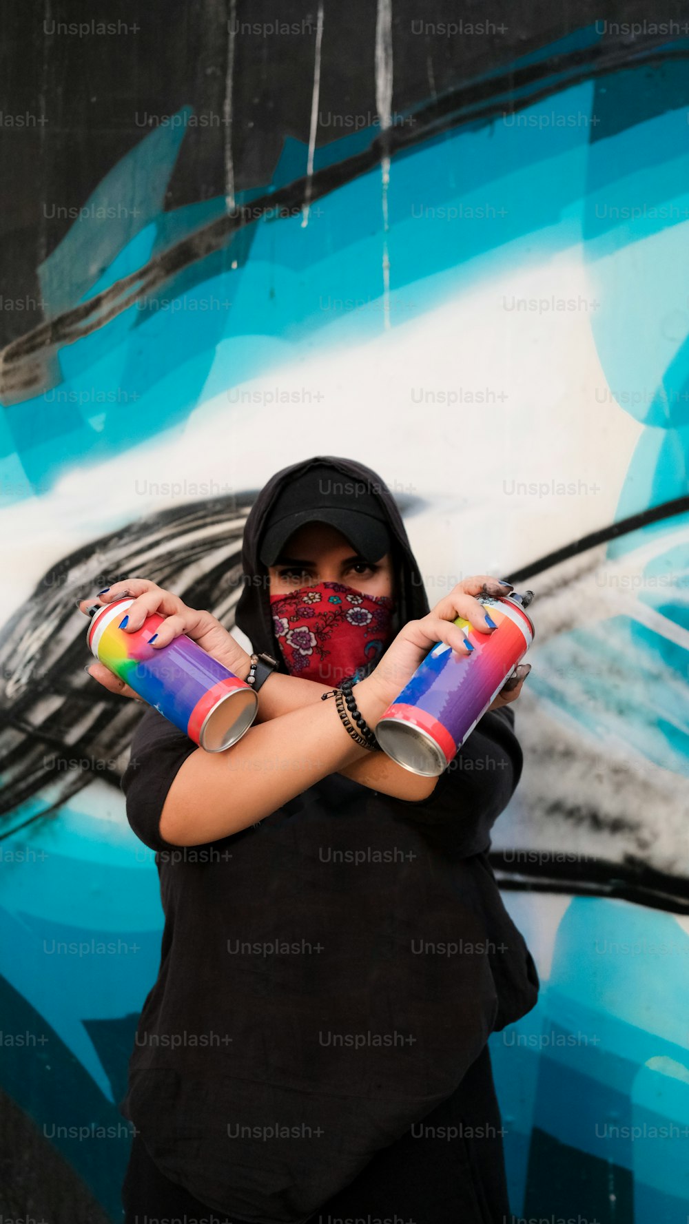 a woman wearing a face mask and holding two cans of paint