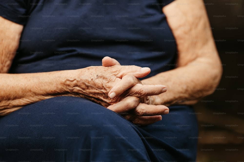 una mujer mayor sosteniendo sus manos juntas