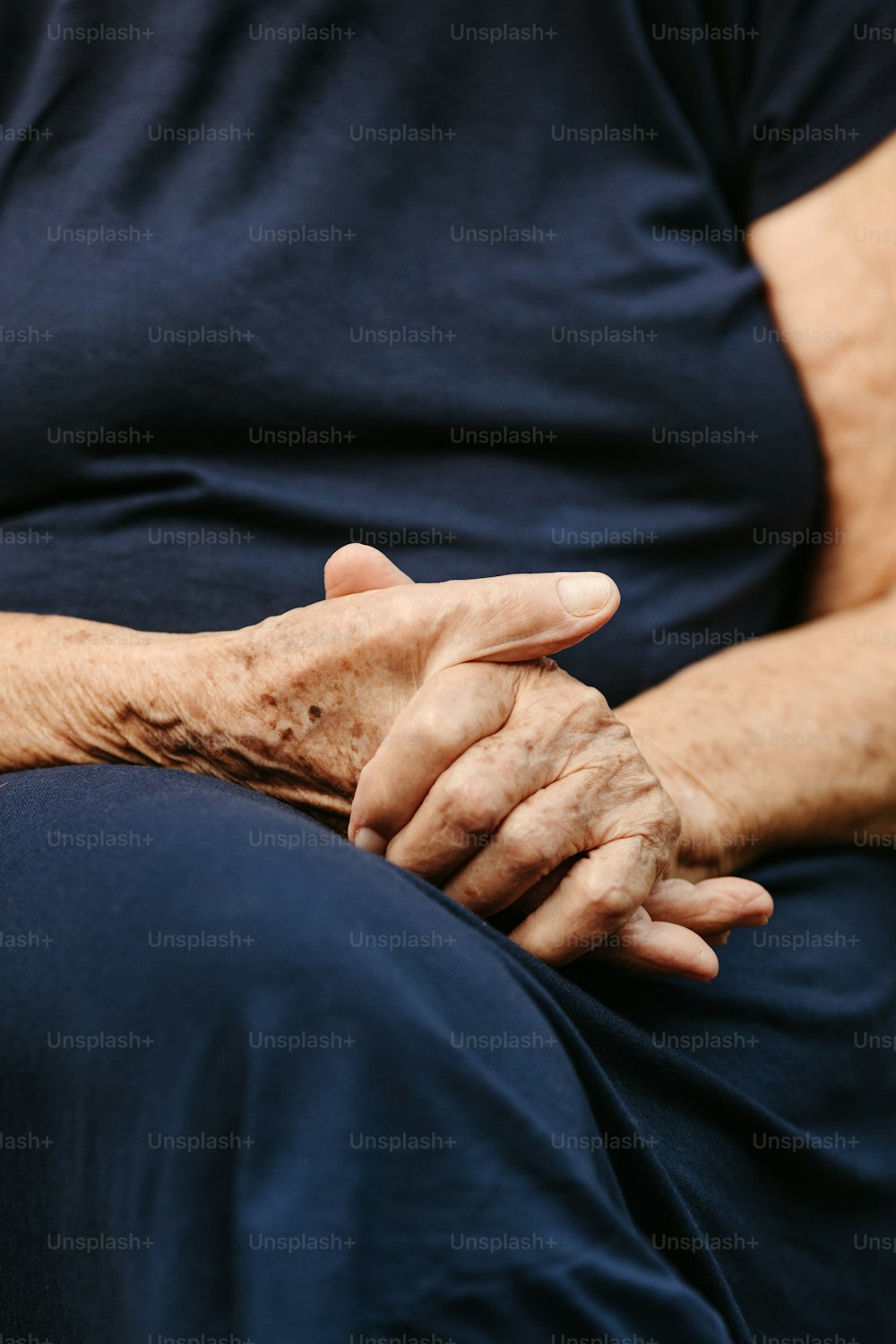 una mujer mayor sosteniendo sus manos juntas
