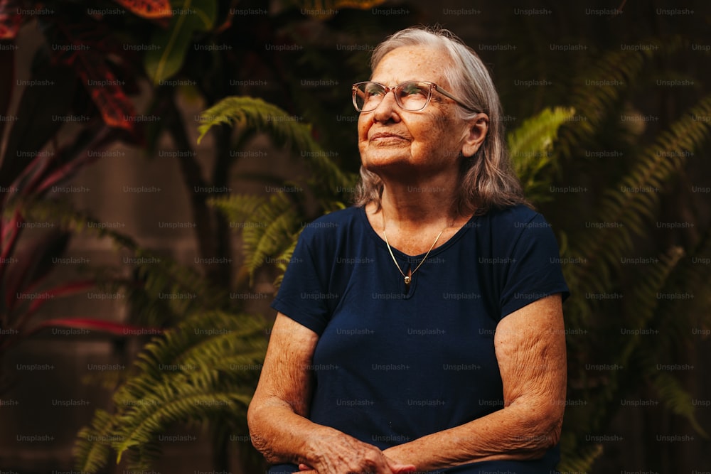 a woman with glasses sitting in front of a plant
