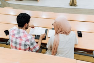 a man and a woman sitting at a table with books