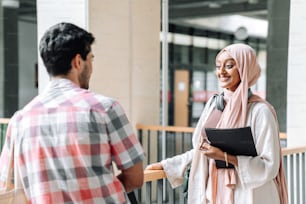 uma mulher de hijab conversando com um homem