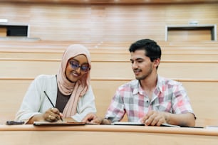 um homem e uma mulher sentados em uma mesa em uma sala de aula