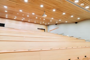 uma sala de aula com assentos de madeira e uma tela de projetor
