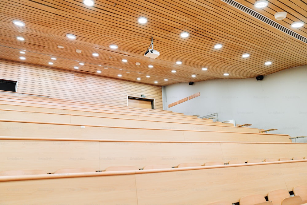 una sala de conferencias con asientos de madera y una pantalla de proyección