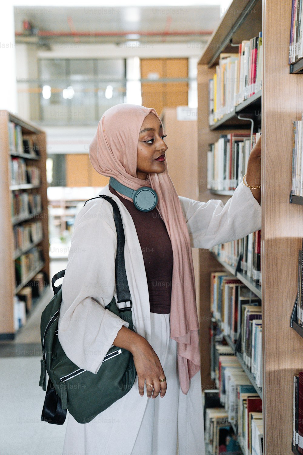 a woman in a hijab is looking at a book shelf
