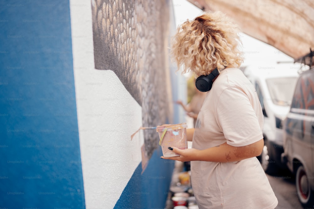 a woman is painting a wall with blue and white paint