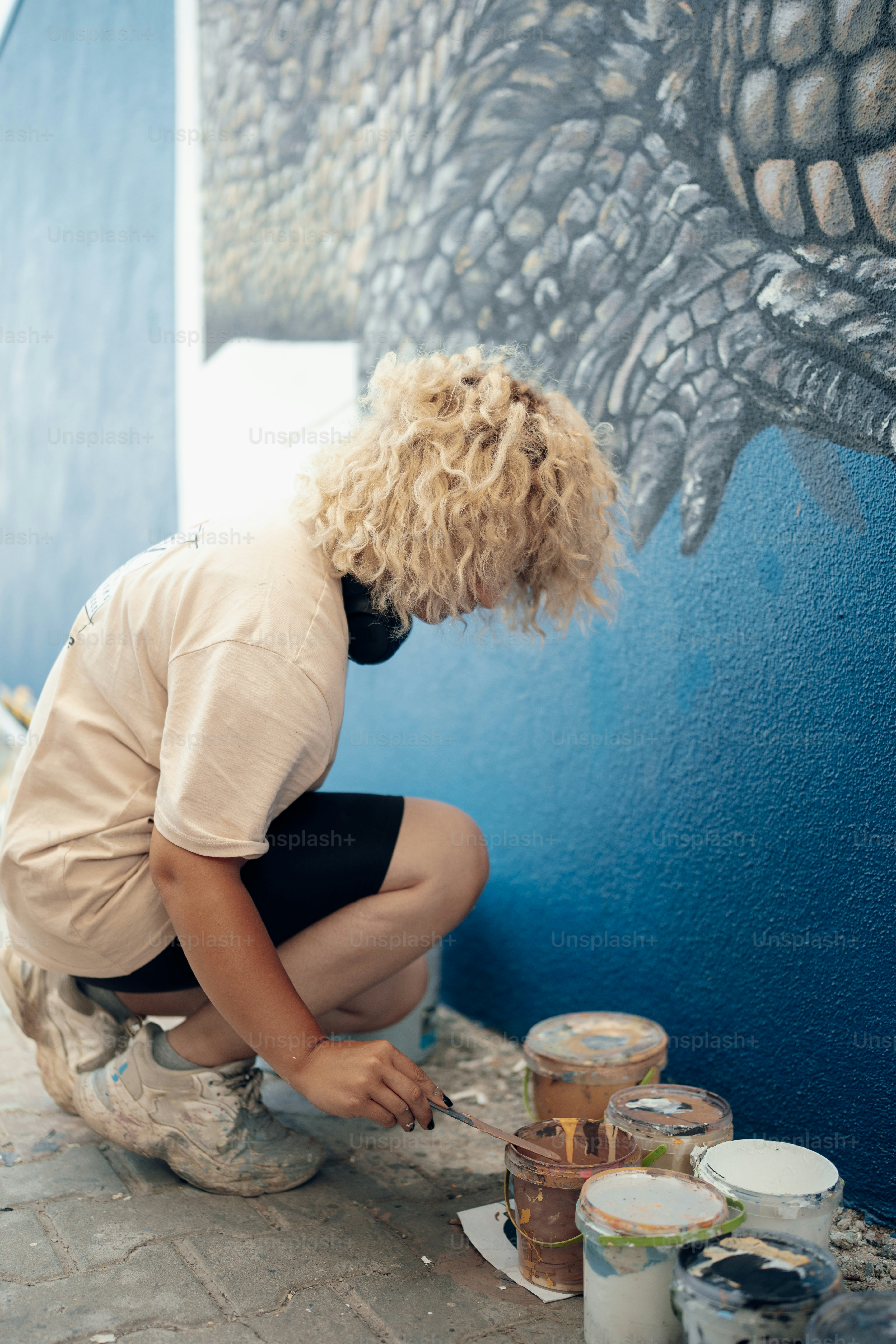 a woman painting a mural on the side of a building
