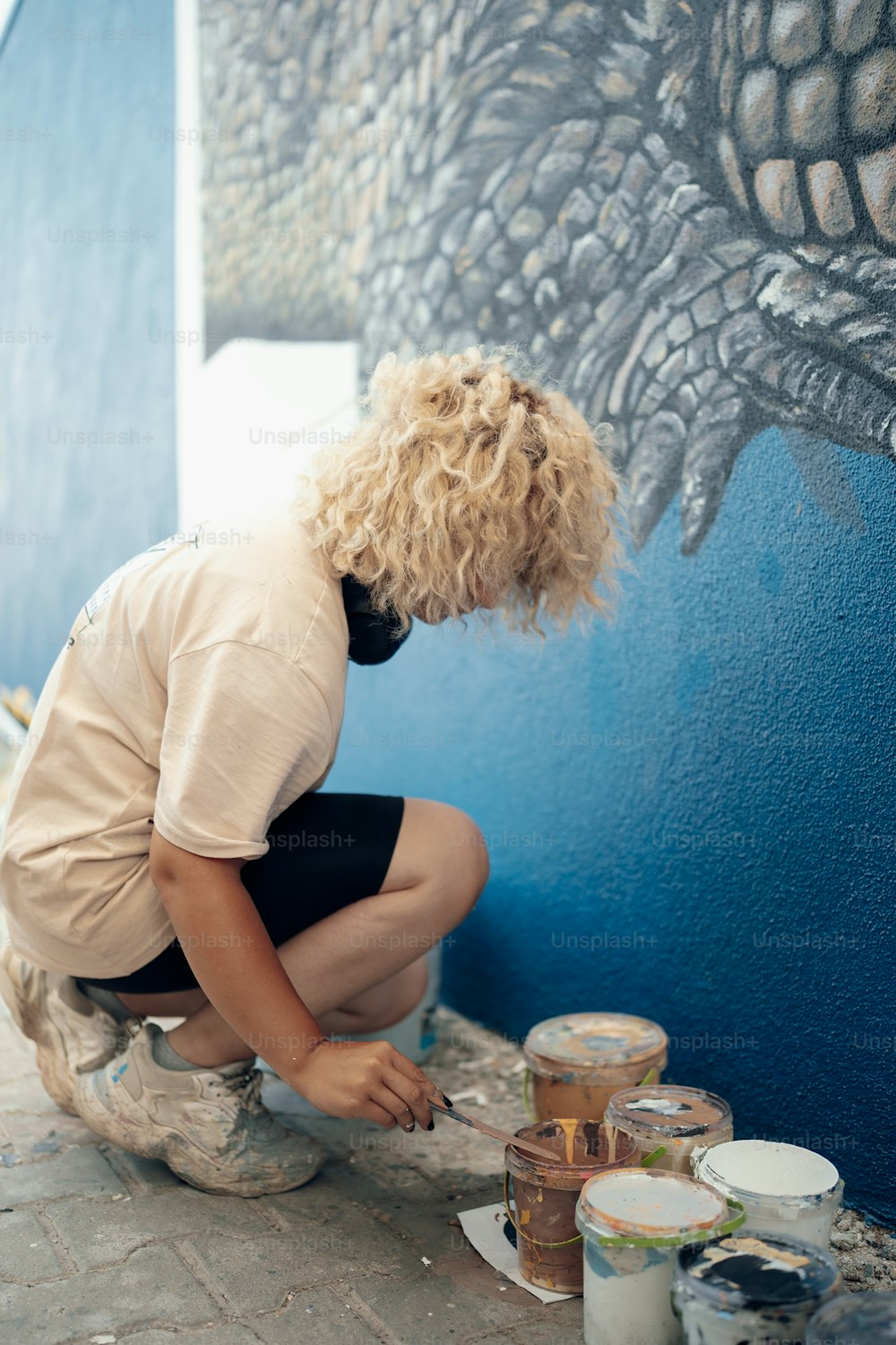 Una donna che dipinge un murale sul lato di un edificio