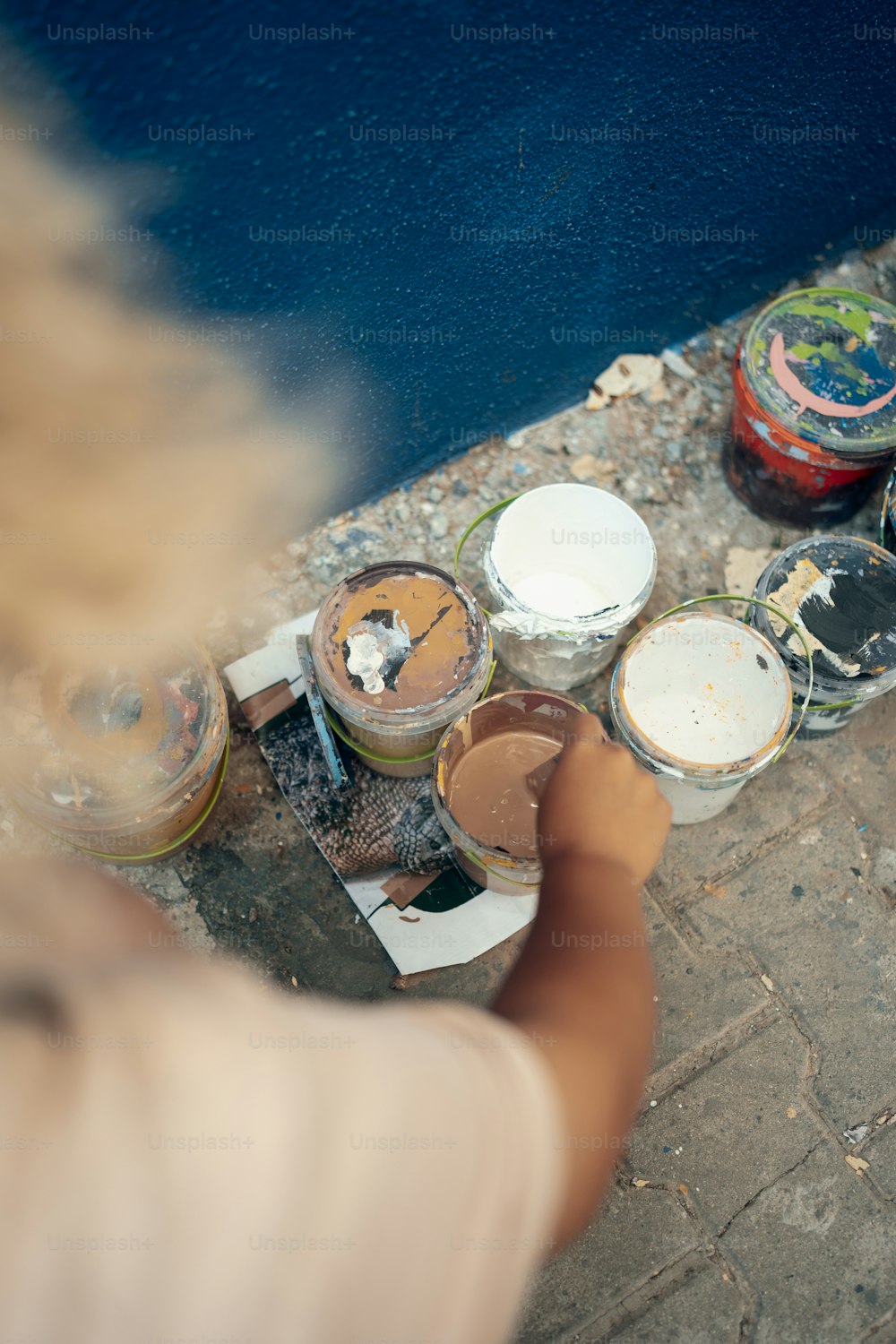 une personne peint un mur avec des pots de peinture