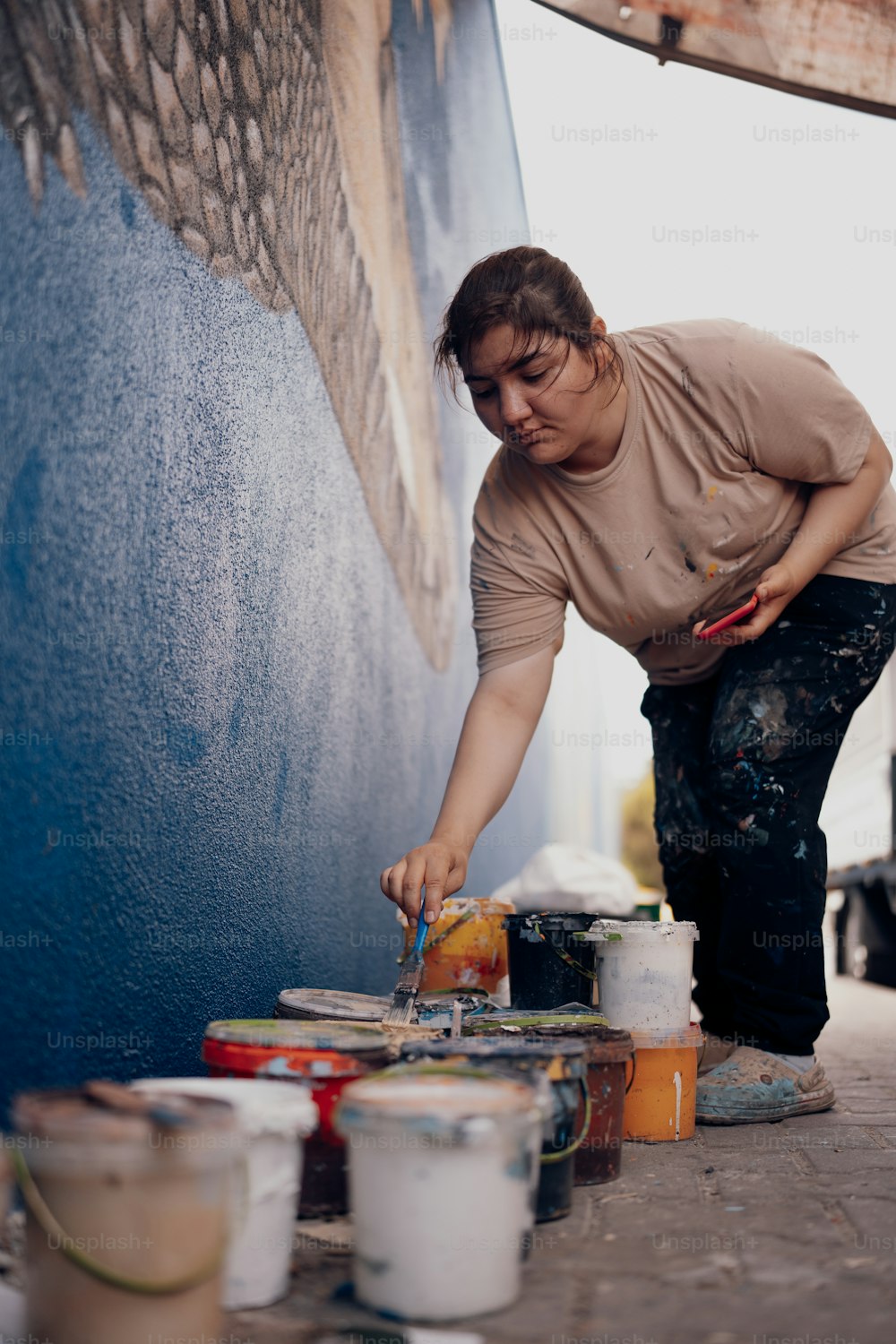 Eine Frau streicht eine Wand mit Farbdosen
