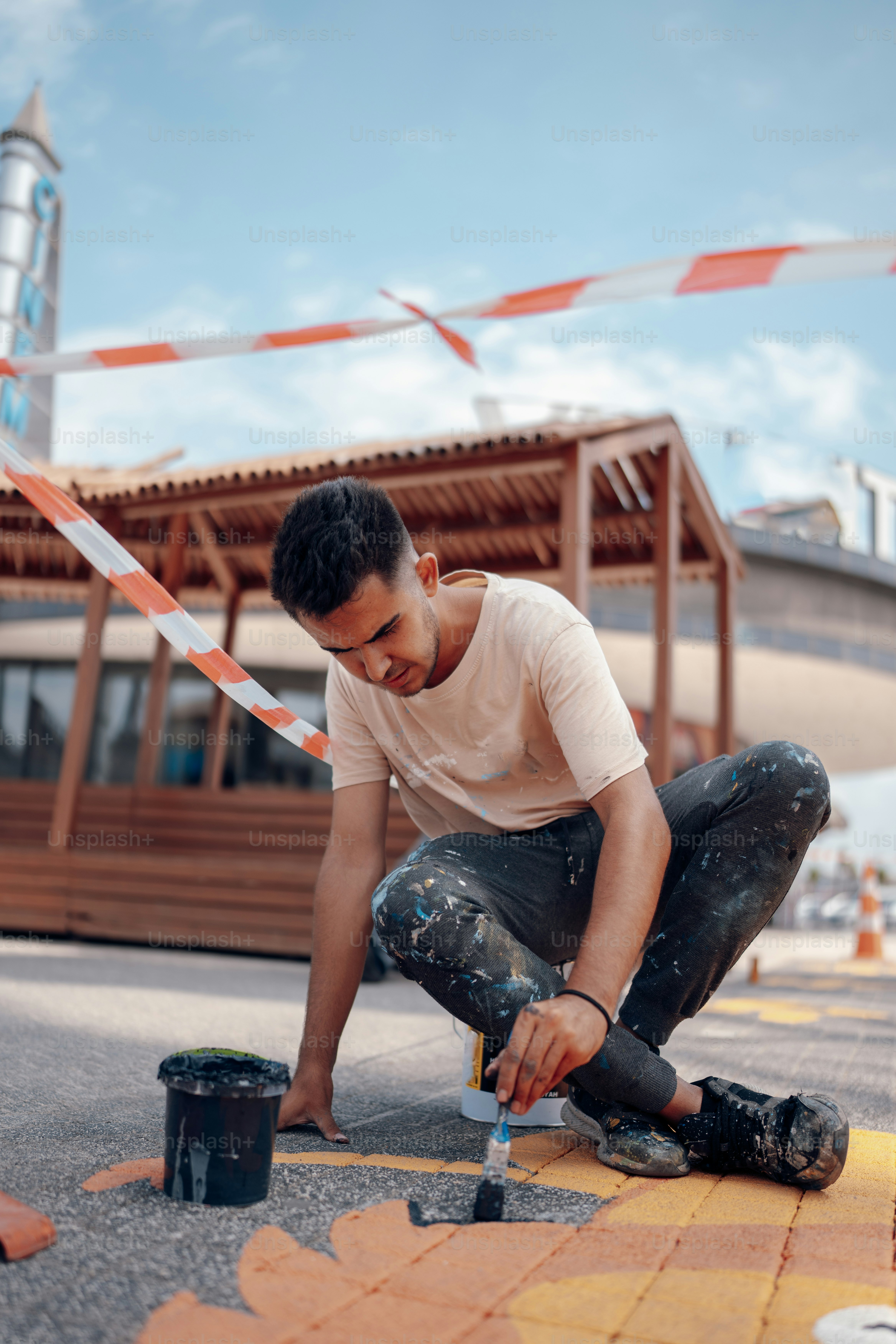 a man kneeling down with a paintbrush and a paint can