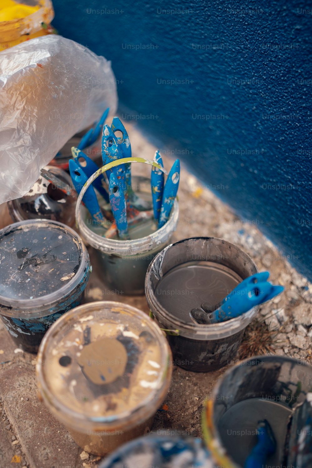 a group of buckets filled with paint sitting next to a wall