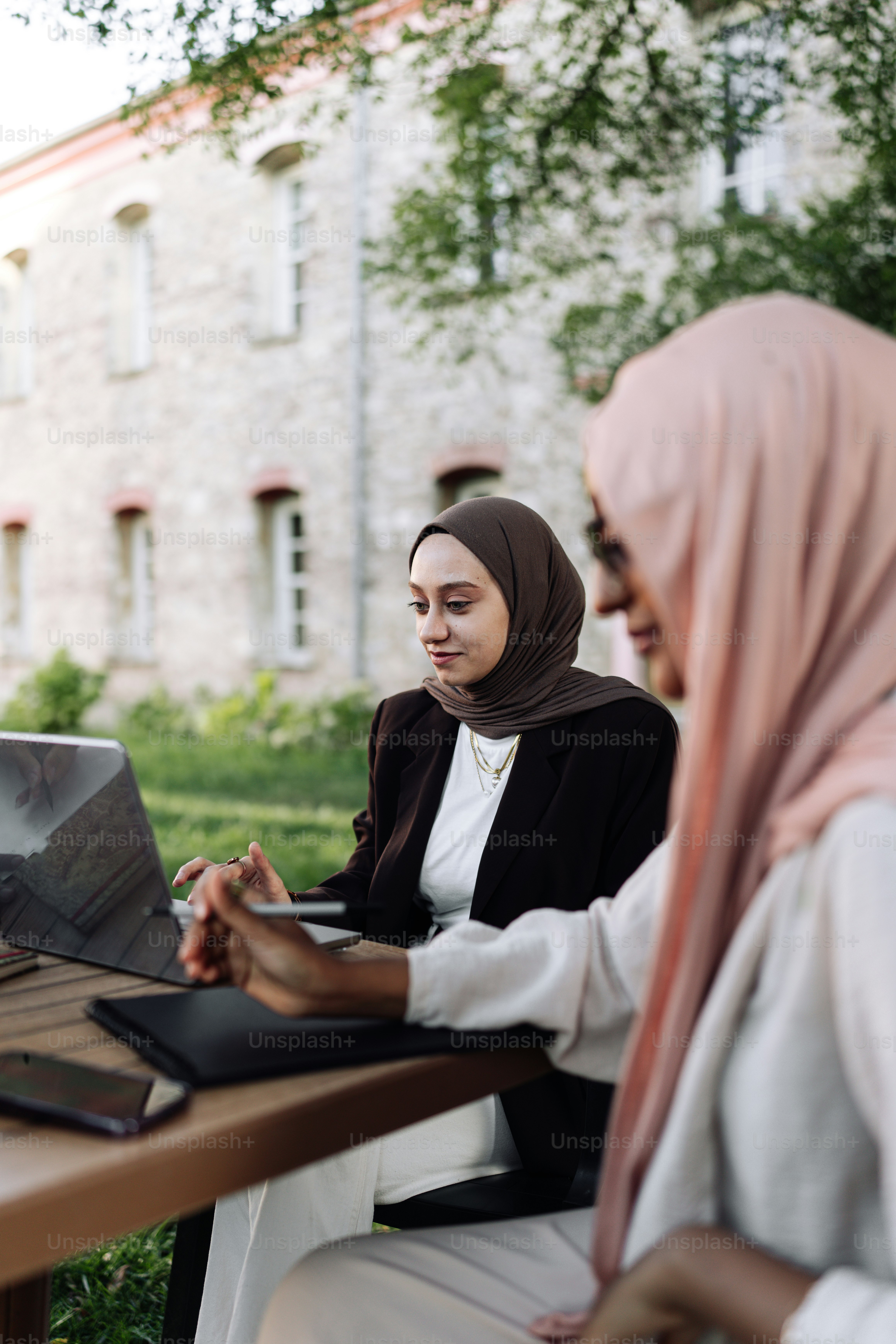 Two women sitting at a table with a laptop photo – Study Image on Unsplash