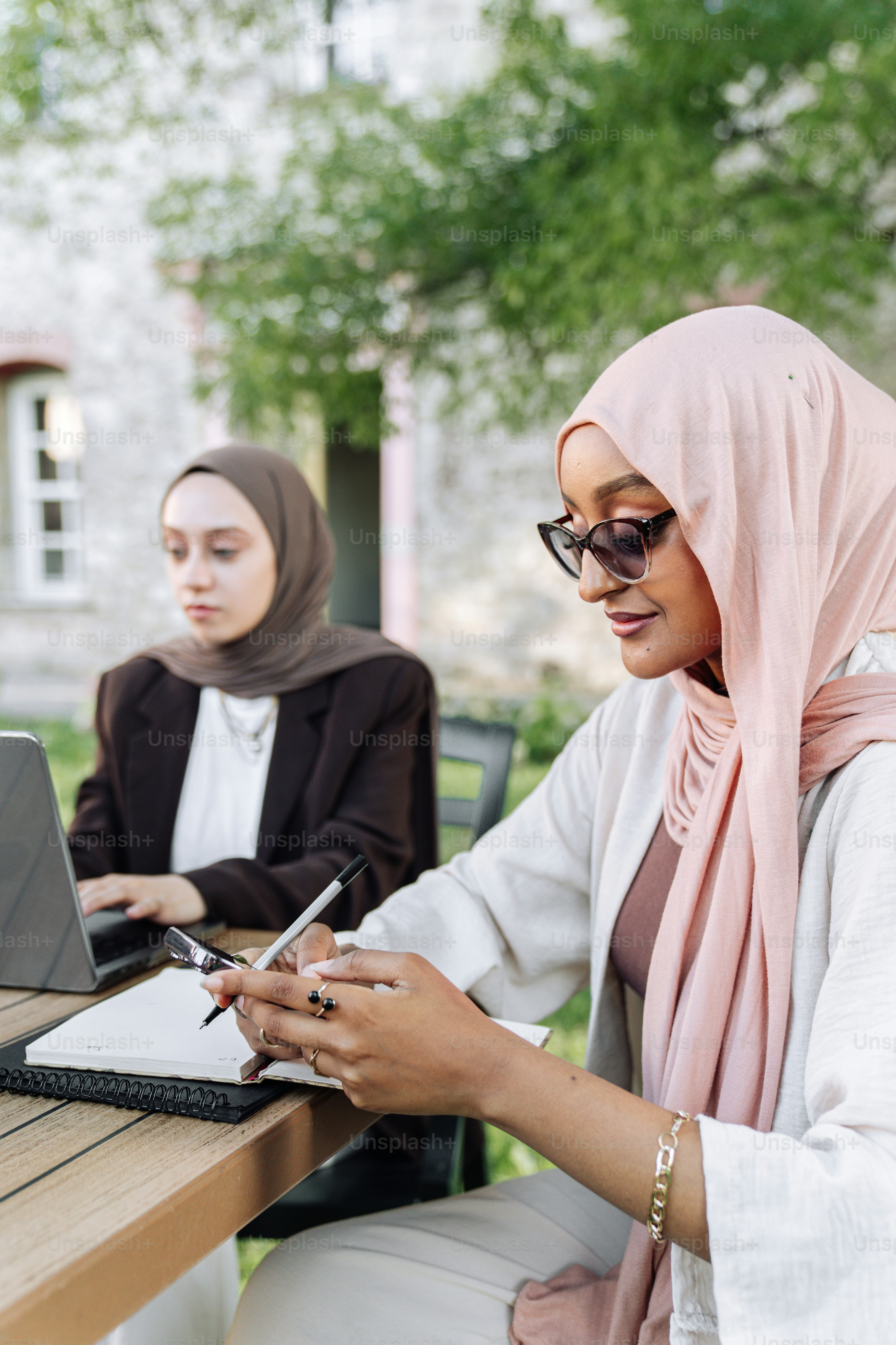 Two women sitting at a table with a laptop photo – Study Image on Unsplash