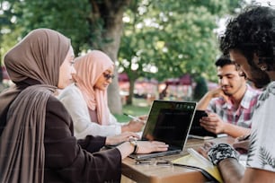 a group of people sitting around a table with a laptop