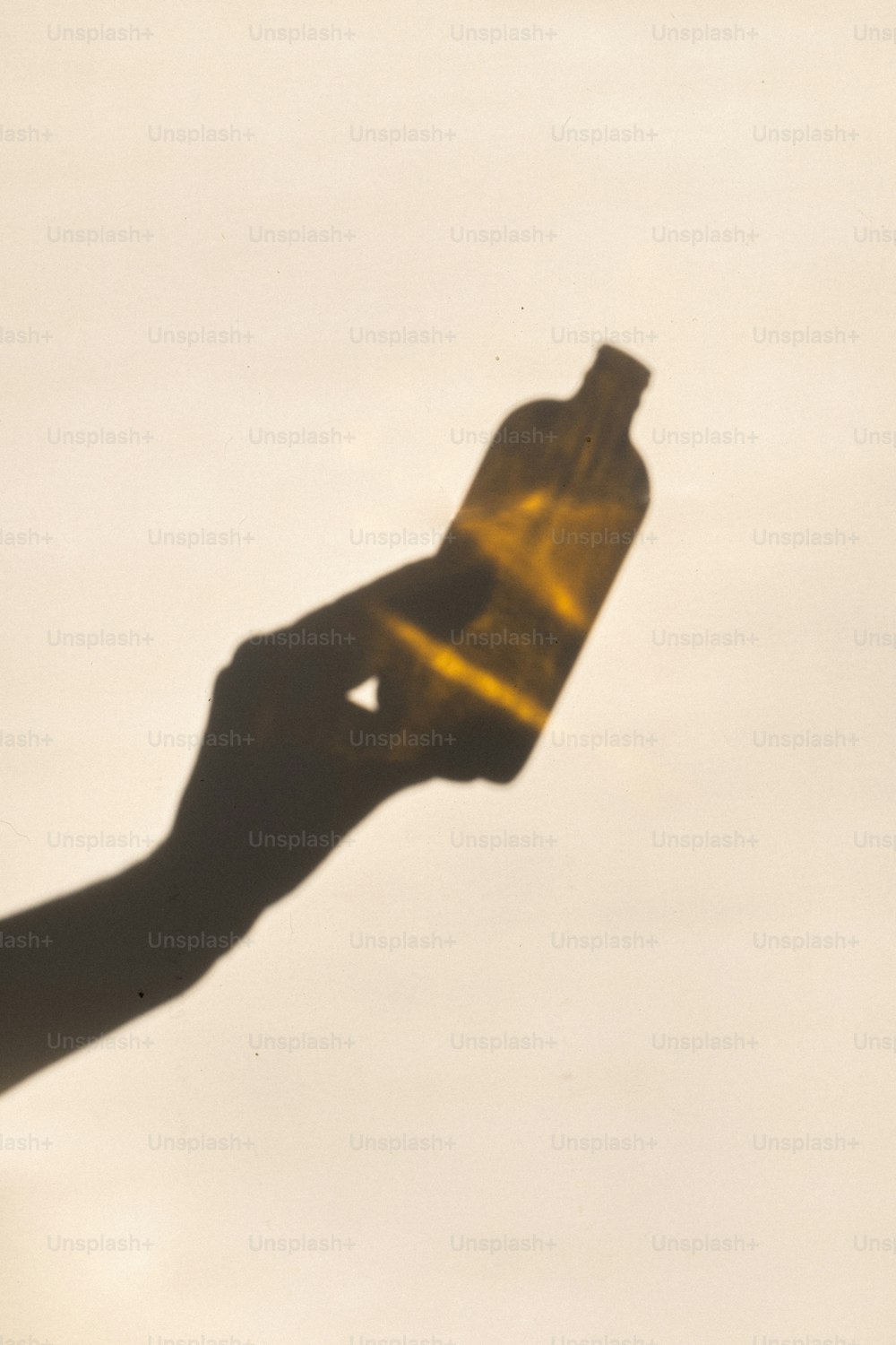 uma sombra de uma mão segurando uma garrafa