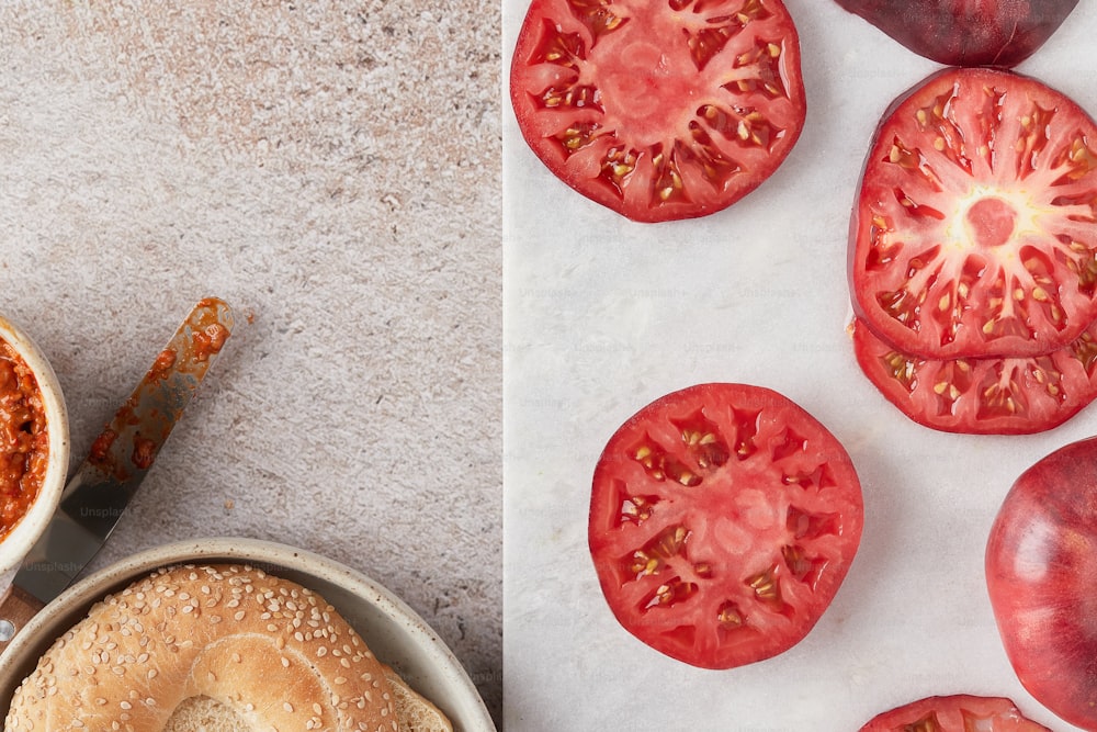 a bagel with tomato slices on top of it next to a bowl of tomato