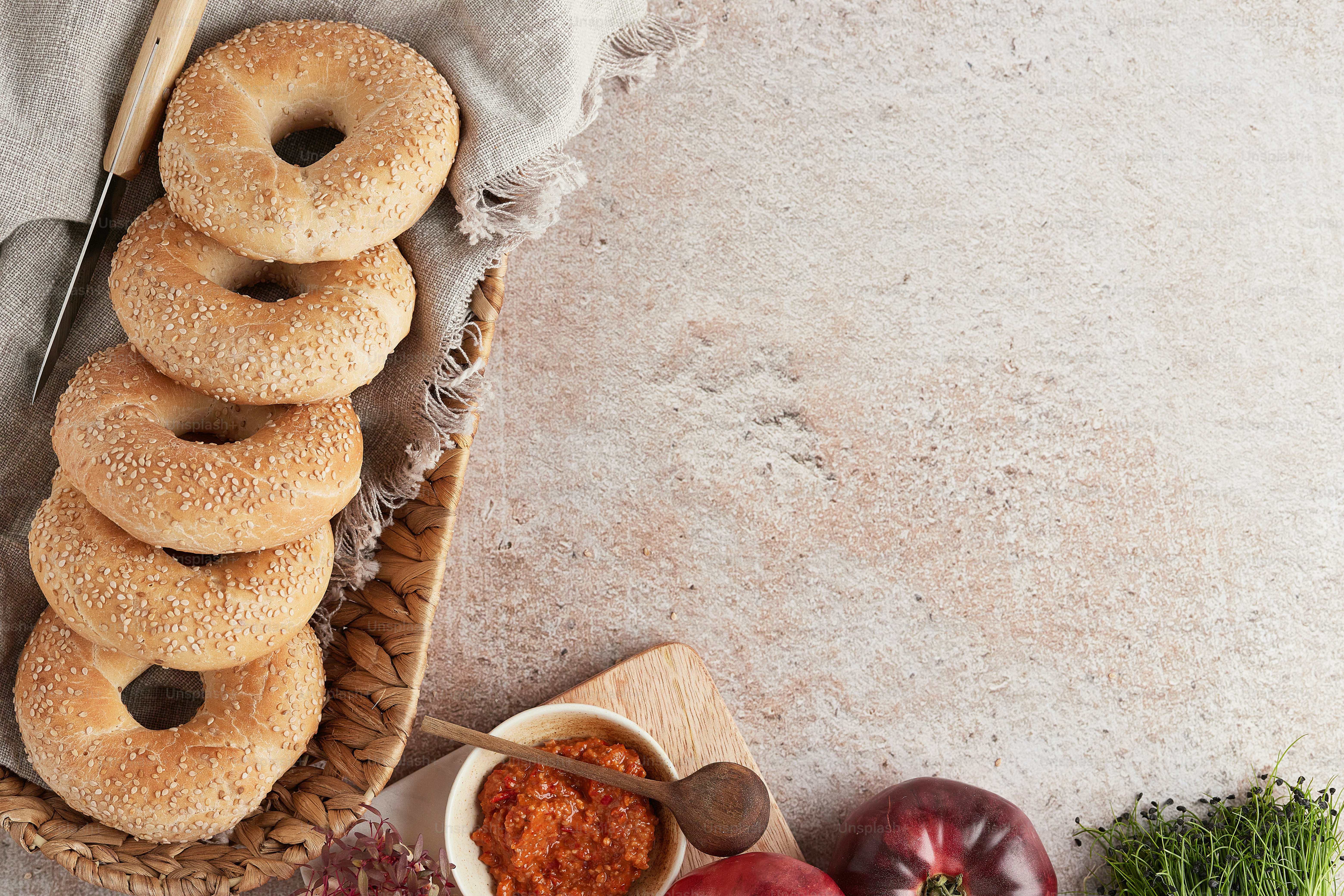 a basket filled with bagels next to a bowl of tomato sauce