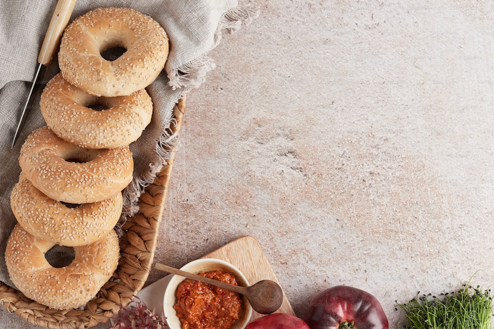 a basket filled with bagels next to a bowl of tomato sauce