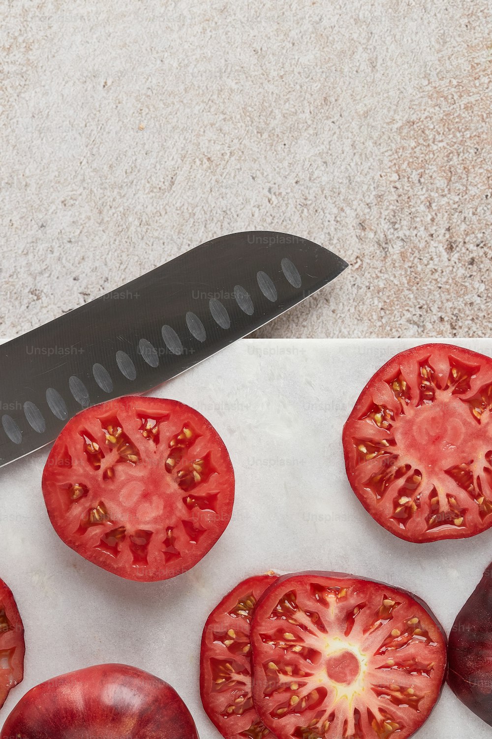 a knife and some tomatoes on a cutting board