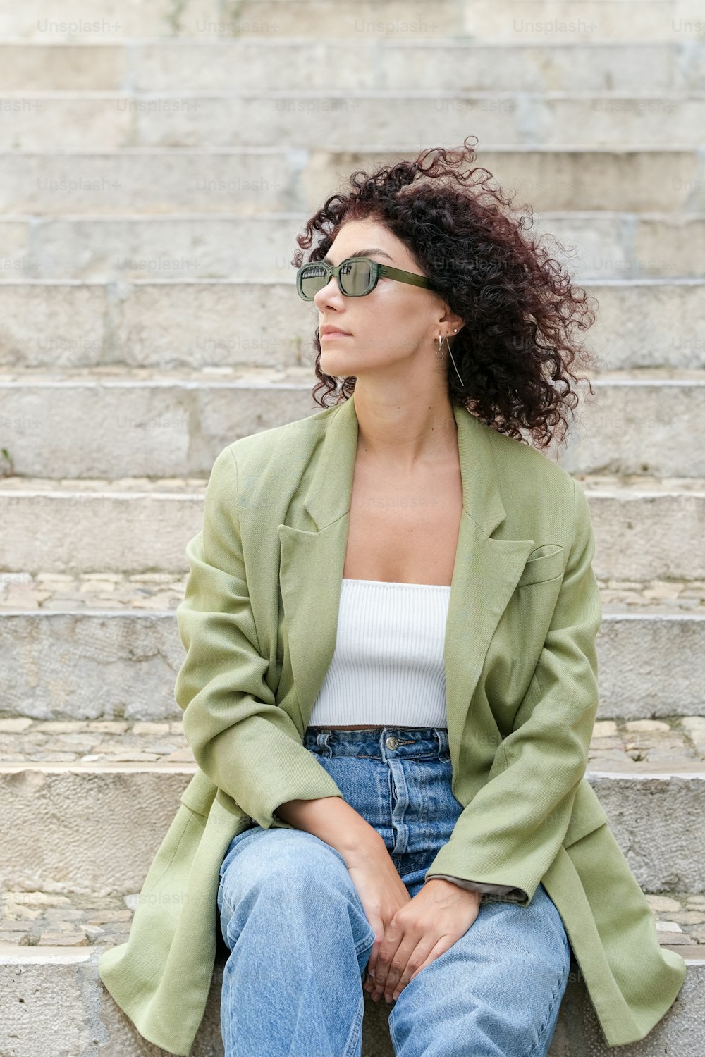 a woman sitting on some steps wearing sunglasses