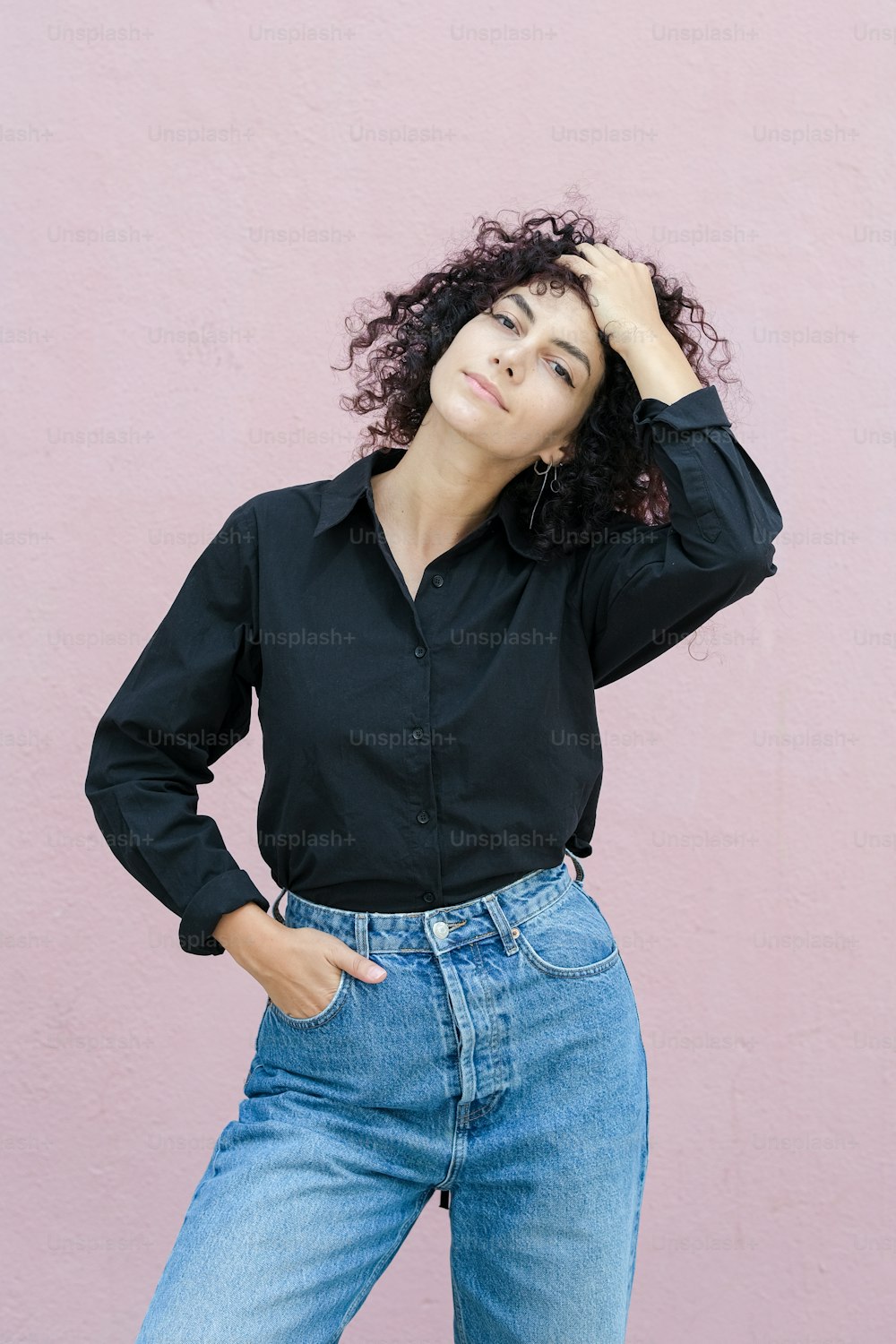 a woman with curly hair wearing a black shirt and jeans