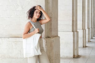uma mulher segurando um saco branco ao lado de uma coluna