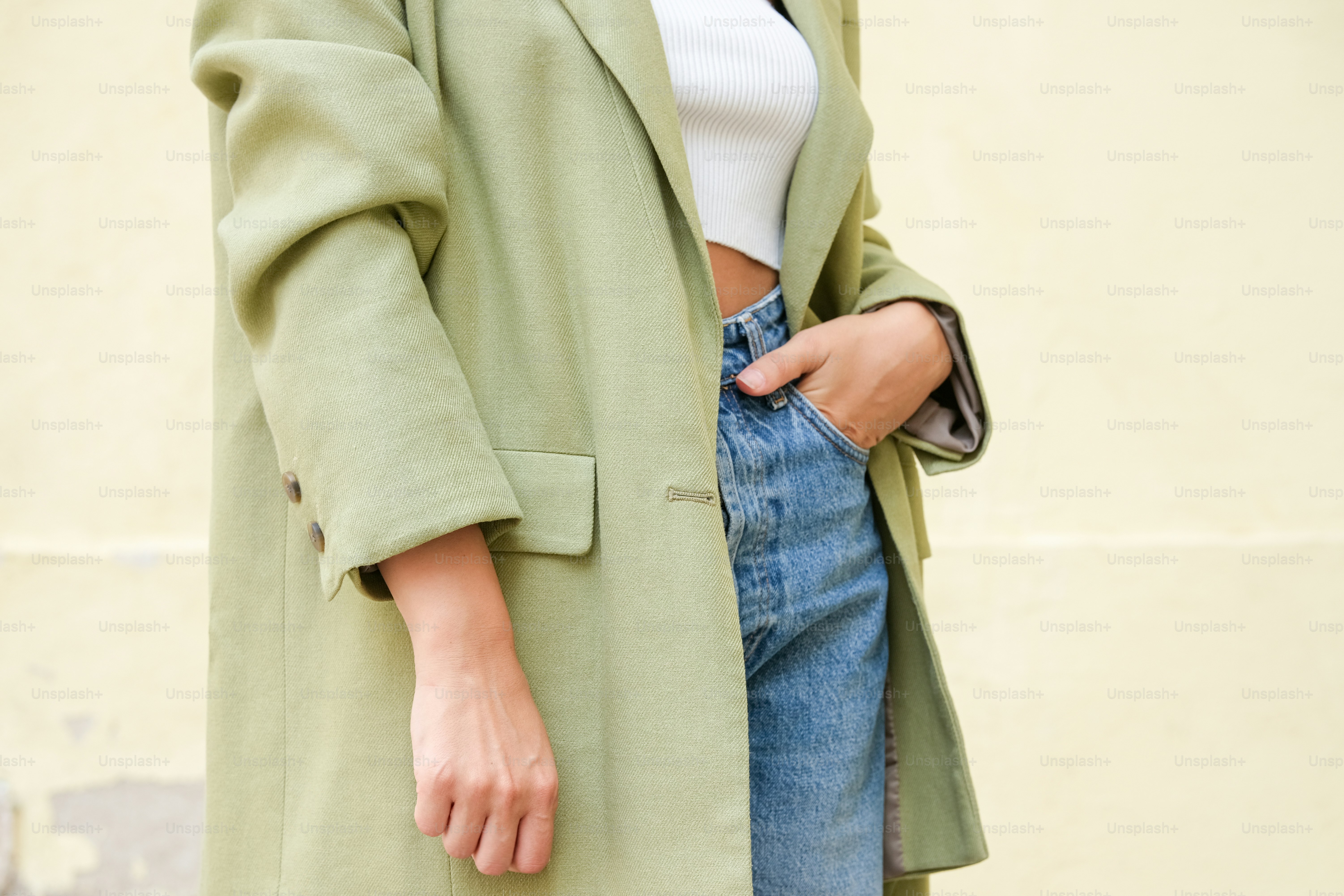 a woman wearing a green coat and jeans