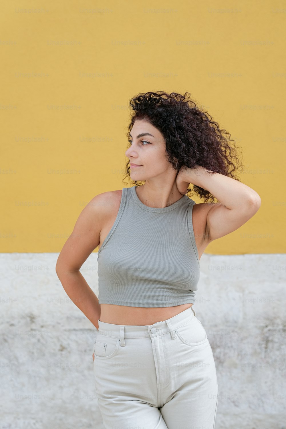 a woman with curly hair standing in front of a yellow wall