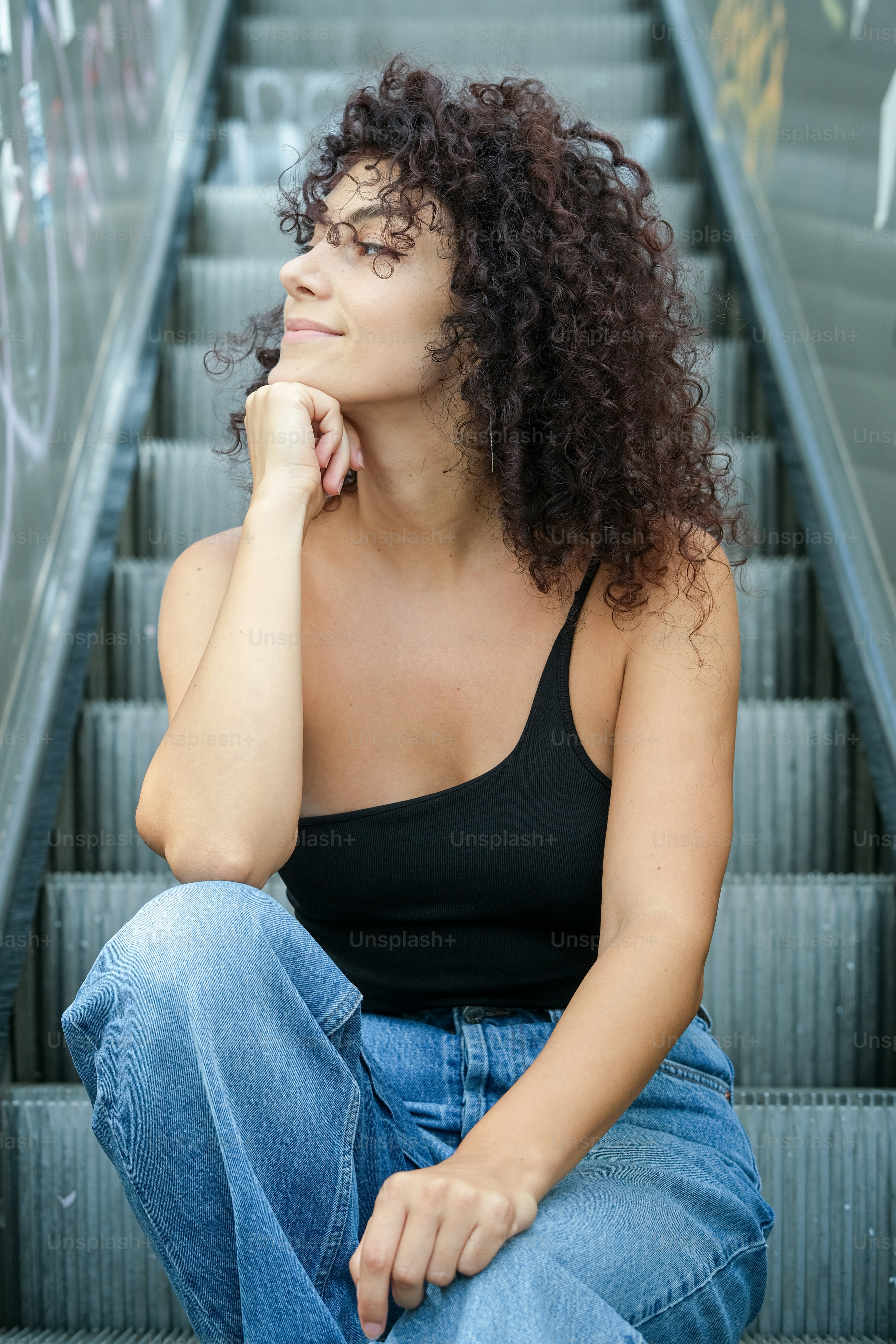 A woman with curly hair sitting on steps photo – Fashion Image on Unsplash