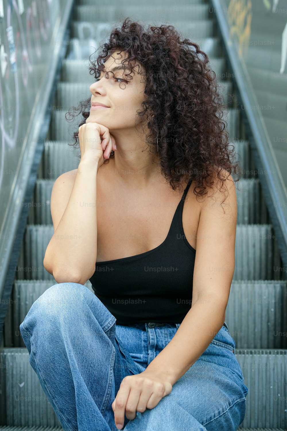 a woman sitting on an escalator with her hand on her chin