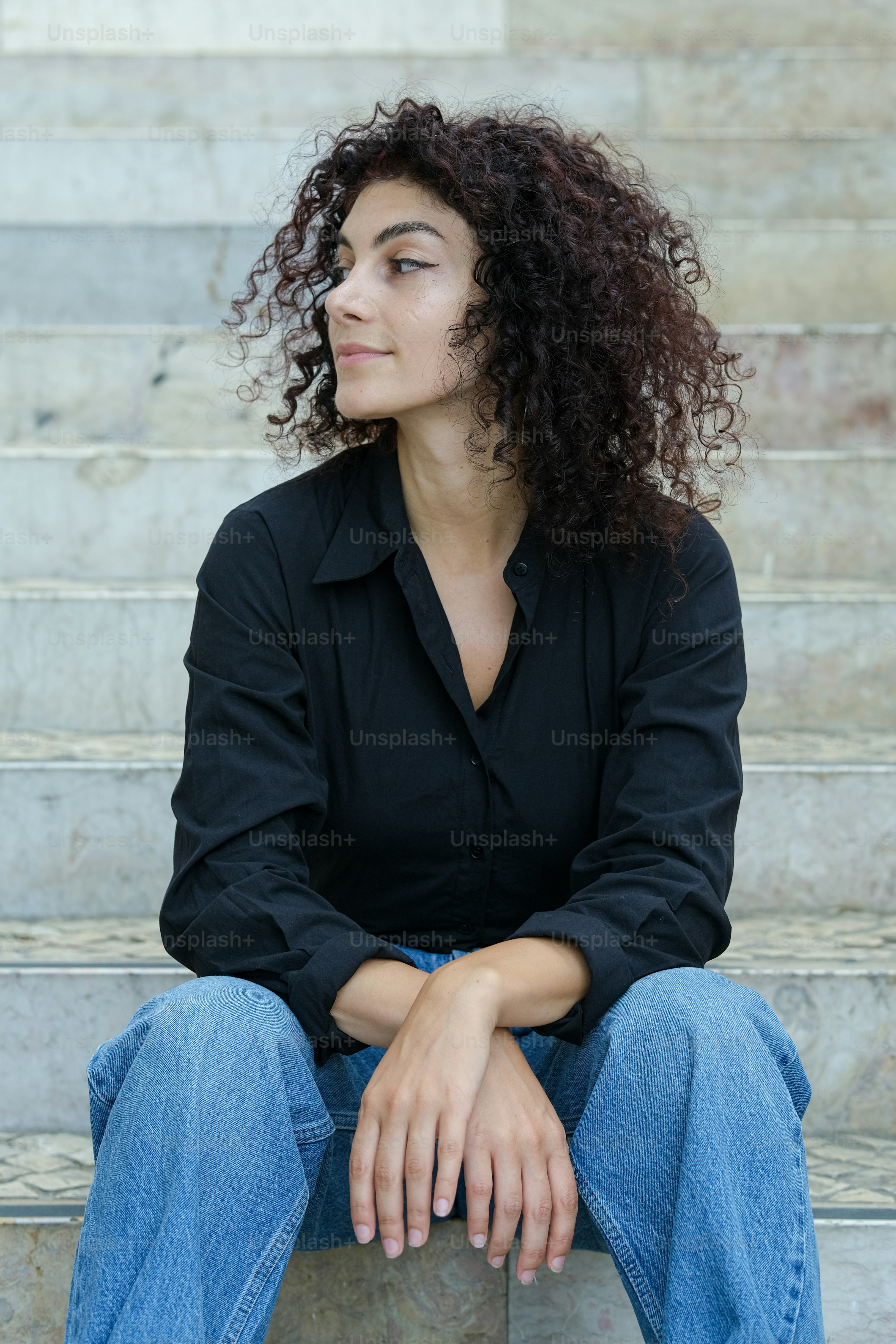 A woman with curly hair sitting on steps photo – Fashion Image on Unsplash