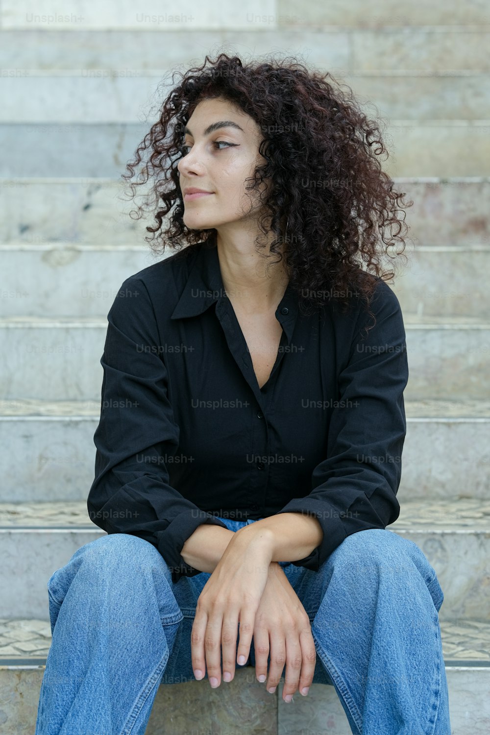 a woman with curly hair sitting on steps