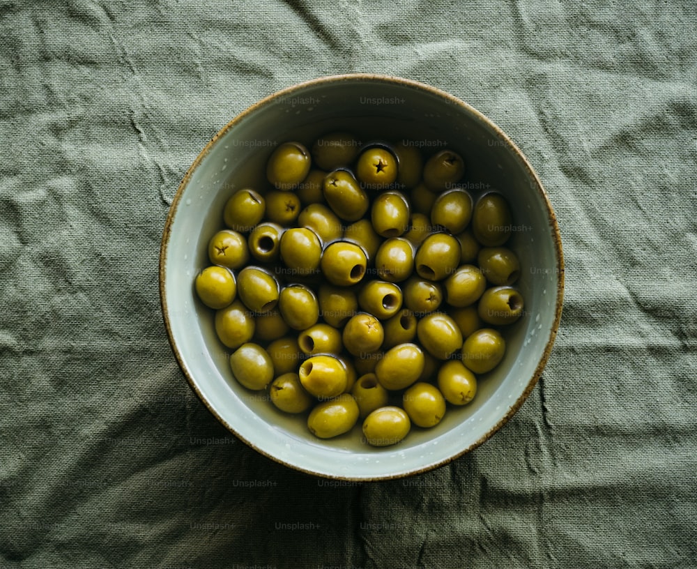 eine mit grünen Oliven gefüllte Schüssel auf einem Tisch