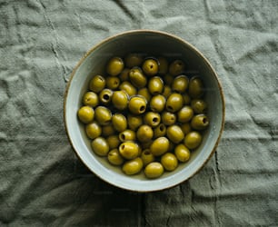 a bowl filled with green olives on a table