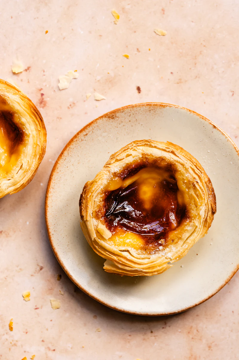Frisch gebackene Pastel de Nata auf einem Teller — goldbraune Kruste