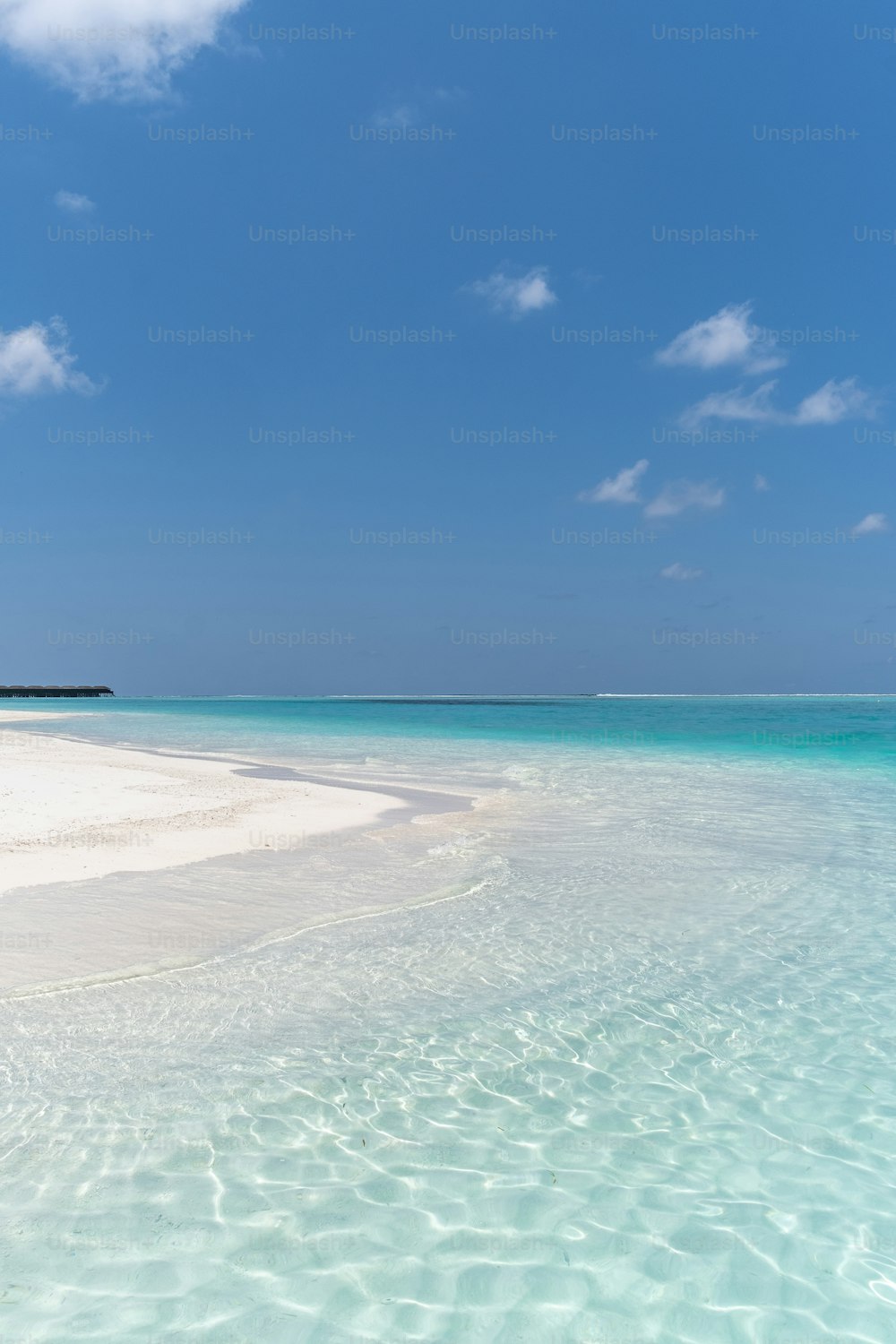 a sandy beach with clear blue water under a blue sky