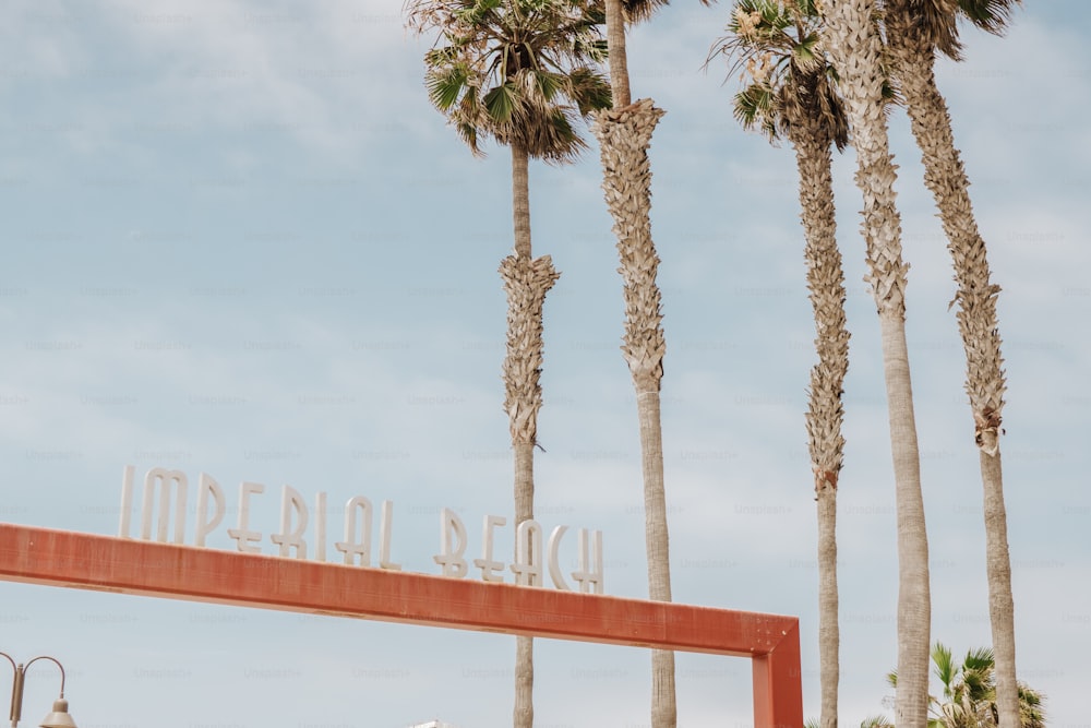 Uma placa que diz Praia Imperial com palmeiras ao fundo
